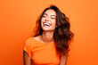 © Enrique - woman smiles in the studio on orange background. happy model. power