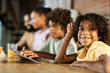© Goran - Happy black girl having fun with her family at dining table and looking at camera