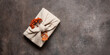 Autumn gift with rowan wrapped in fabric on brown rustic background. A traditional furoshiki gift. Top view, flat lay, copy space. Banner