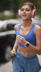 Wall Mural - A young woman in sportswear and headphones is running through the streets of the city.