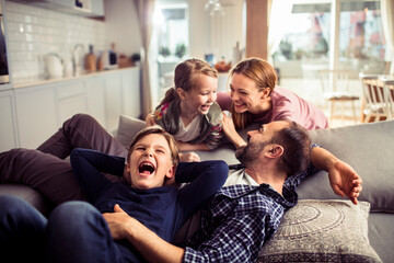 Young Caucasian family playing and having fun on the couch at home