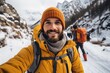 © Nanci - A smiling young hiker man taking a selfie in the snowy mountains. Winter travel and outdoor activities concepts.