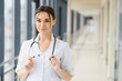 © Serhii - Portrait of young female doctor standing in hospital corridor. Caucasian woman working in nursing home.