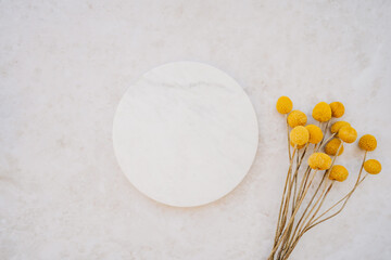 Wall Mural - White marble cosmetic podium product design and bouquet of dry yellow flowers on white marble background