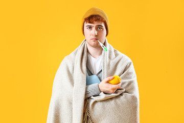 Sticker - Ill young man with thermometer, lemon and hot water bottle on yellow background