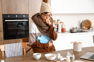 Sticker - Ill Asian man with hot water bottle in kitchen