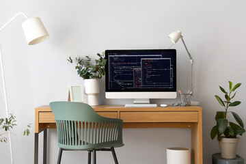 Programmer's workplace with computer and eucalyptus in light office