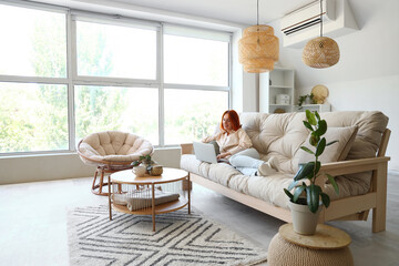 Sticker - Young woman using laptop on couch in living room