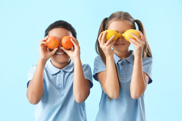 Happy little children with fresh citruses on blue background