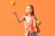 Leinwandbild Motiv Little girl with fresh oranges on orange background