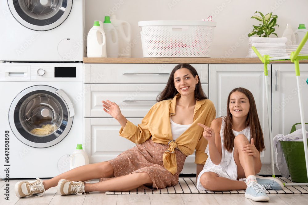 Happy mother with her little daughter in laundry room
