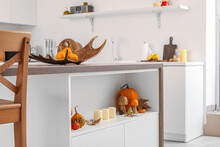 Table With Halloween Pumpkins, Candles And Fallen Leaves In Kitchen