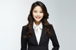 © Surachetsh - A confident and clever young Asian woman, dressed in a dark gray suit paired with a crisp white shirt, delivers a presentation on a White gray backdrop. Generative AI.
