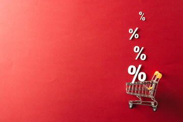 Poster - Shopping trolley and white percent signs with copy space on red background