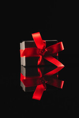 Wall Mural - Black gift box with ribbon and copy space over black background