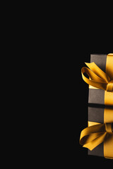 Wall Mural - Black gift box with ribbon and copy space over black background