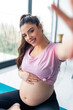 © DusanJelicic - Beautiful pregnant young woman taking a picture of herself using her phone in a pink shirt