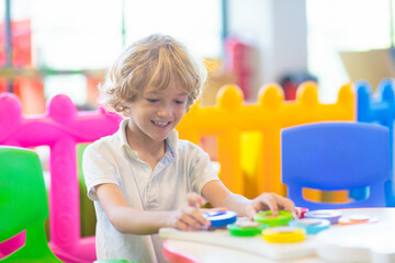 Little boy in with toys in school classroom.