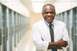 © Nino Lavrenkova - Portrait of smiling old black male doctor standing with arms crossed in hospital corridor