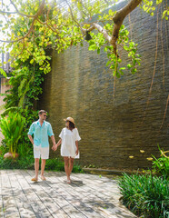 Wall Mural - couple vacation luxury resort walking in a tropical garden with green palms and palm trees