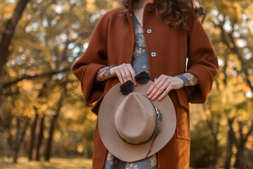 attractive stylish woman walking in park dressed in warm brown coat