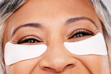 Poster - Closeup, woman and eyes with patches in skincare, cosmetics or anti aging against a studio background. Face of female person or model with eye pads, mask or product for facial treatment or routine