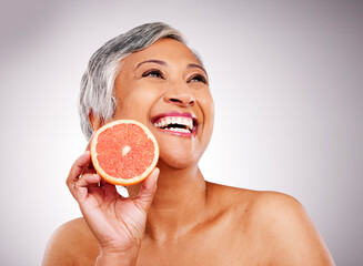 Sticker - Senior, happy woman and grapefruit for vitamin C, skincare or natural nutrition against a studio background. Mature female person smile with organic citrus fruit for collagen, detox or diet on mockup