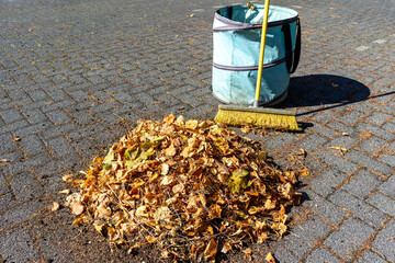 Wall Mural - Pile of leaves with broom and basket in a park