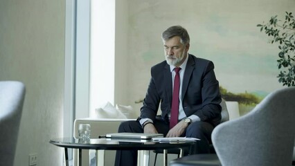 Wall Mural - Businessman using laptop computer in office lobby or on cafe terrace. Happy mature man, entrepreneur, small business owner working online