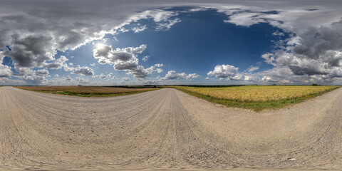 Wall Mural - 360 hdri panorama on gravel road with marks from car or tractor tires with clouds on blue sky in equirectangular spherical  seamless projection, skydome replacement in drone panoramas