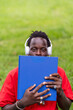 © Ceballos - Young Black Man's Peaceful Moment with a Blue Book and White Headphones