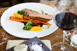 Duck fillet with sweet potato cream, roasted carrots, kale, beet-port sauce on white plate. Grilled and roasted poultry closeup served on a table for lunch in modern cuisine gourmet restaurant.