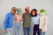 © Studio Romantic - Team of strange people disguised as funny animals. Studio portrait of young men and women wearing crazy eccentric dinosaur, bird, horse, ape and frog masks standing together and hugging each other