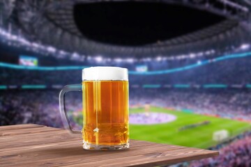 Wall Mural - Glass of fresh cold alcohol beer on stadium background