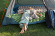 tired barefoot child sleeps or rests lying on his stomach in a tent with his favorite toy teddy bear. Healthy lifestyle, little tourist, family activities, summer fun
