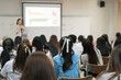 © EduLife Photos - Rear view of college students listen to teacher teaching and explaining lesson in classroom