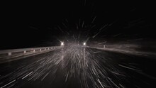Car driving down the highway at night on snowstorm blizzard slippery road. Pov through through the windshield on falling snow snowflakes on low visibility winter storm.
