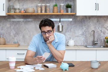 Wall Mural - Close up of unhappy man sitting at the table, stressed and confused by calculate expense from invoice or bills, have no money to pay mortgage or loan. High prices and spending money concept