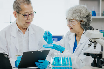 Wall Mural - Two Asian scientists in the laboratory or medical personnel looking at a microscope in the lab