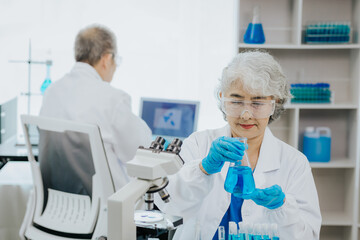 two asian scientists in the laboratory or medical personnel looking at a microscope in the lab