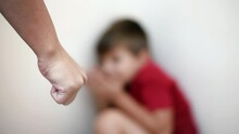 Close View Of An Adult's Fist And Scared Child On The Background