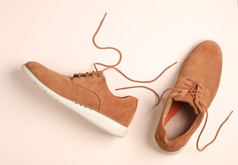 Poster - Men's suede shoes with untied laces on beige background