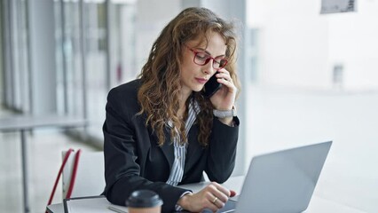 Poster - Young woman business worker using laptop talking on smartphone at the office