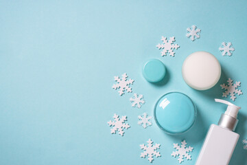 Wall Mural - winter cosmetic with knitting scarf on blue background. flat lay with copy space.