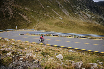 Male cyclist riding a gravel bike in the mountainous terrain on a foggy day.Man cyclist wearing cycling kit and helmet.Motivation image of an athlete.Cyclist enjoying traveling on his bike.Transalpina