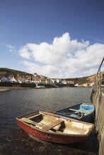 Rowboats Tied Along The Shore With Houses Along The Waterfront; Staithes, Yorkshire, England