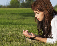 Young Woman Praying With Her Bible In A Park; Edmonton, Alberta, Canada