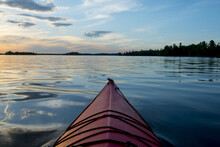 Bow Of A Canoe On A Tranquil Lake At Sunset; Ontario, Canada