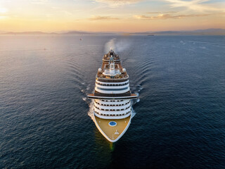 Wall Mural - aerial view of a cruise ship traveling over the ocean during summer sunset time