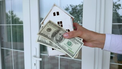 Wall Mural - American dollars and small house in the hands. Concept of business in a real estate